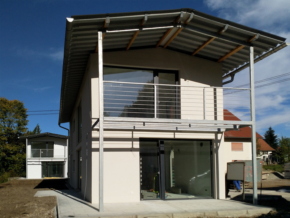Réalisation d'un façade d'immeuble minimaliste en stuc de taille moyenne avec un toit à deux pans et un toit en métal.