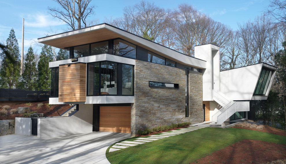 Ispirazione per la facciata di una casa contemporanea a due piani con rivestimento in pietra e terreno in pendenza
