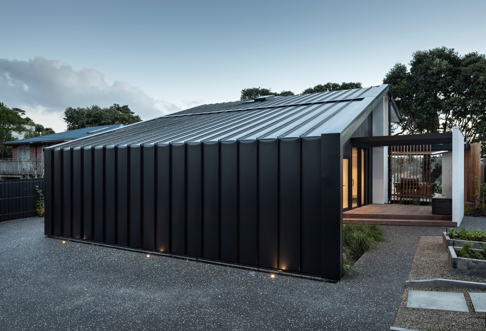 Cette photo montre une façade de maison noire tendance de taille moyenne et à un étage avec un revêtement mixte et un toit en métal.