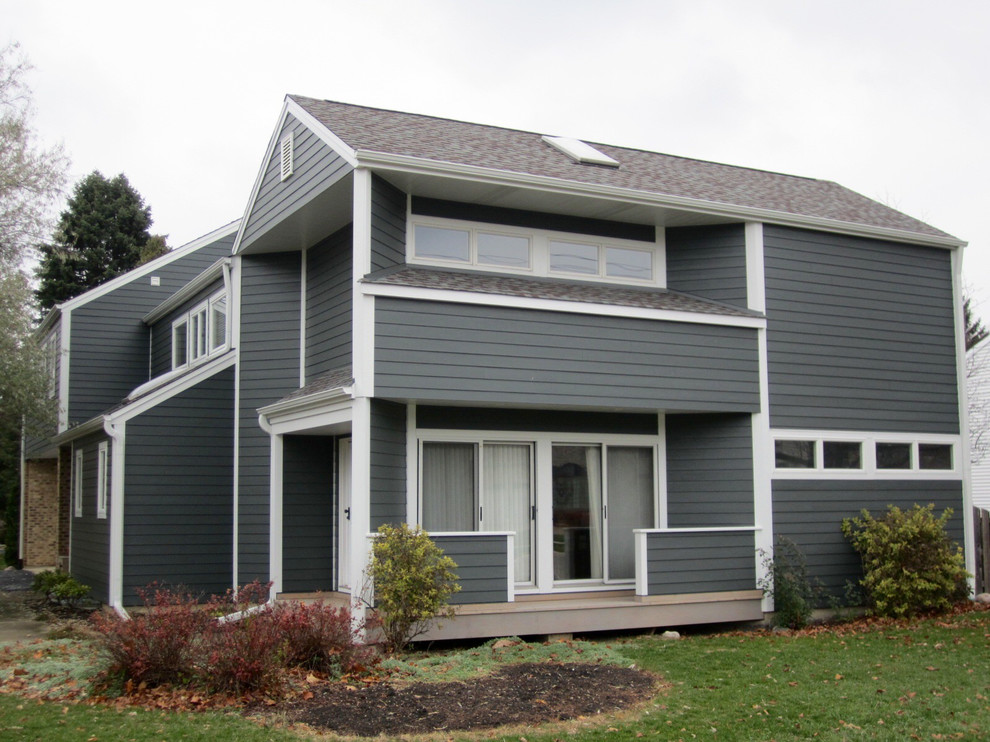 Mittelgroßes, Zweistöckiges Landhaus Einfamilienhaus mit Faserzement-Fassade, grauer Fassadenfarbe, Satteldach und Schindeldach in Sonstige