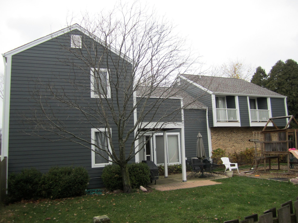 Пример оригинального дизайна: двухэтажный, серый частный загородный дом среднего размера в стиле кантри с облицовкой из ЦСП, двускатной крышей и крышей из гибкой черепицы
