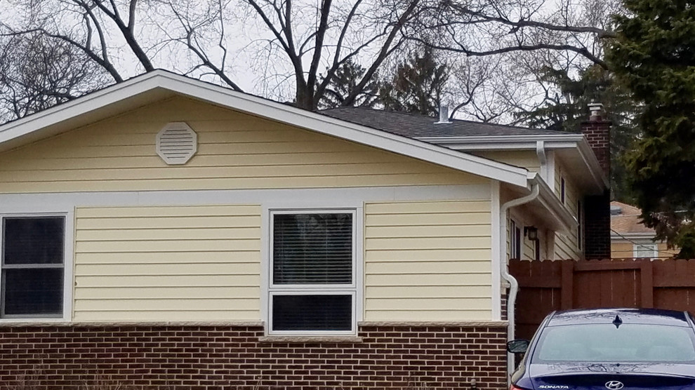 Mittelgroßes Klassisches Einfamilienhaus mit Vinylfassade, gelber Fassadenfarbe und Schindeldach in Chicago