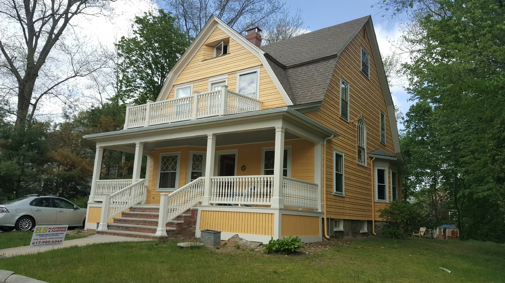 На фото: большой, трехэтажный, деревянный, желтый дом в викторианском стиле с мансардной крышей