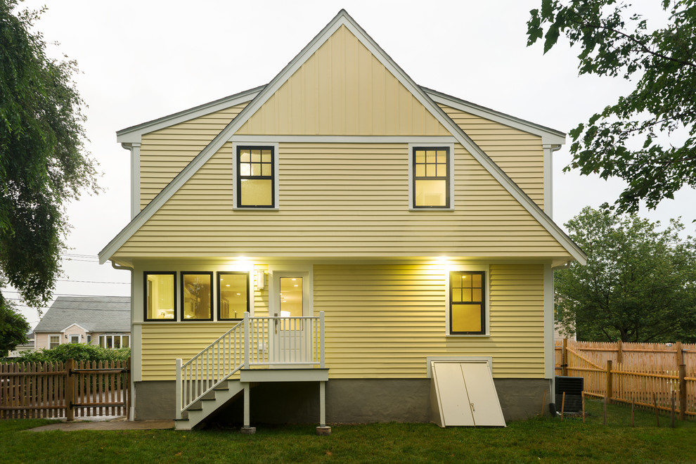 На фото: двухэтажный, желтый частный загородный дом среднего размера в стиле неоклассика (современная классика) с облицовкой из винила и двускатной крышей