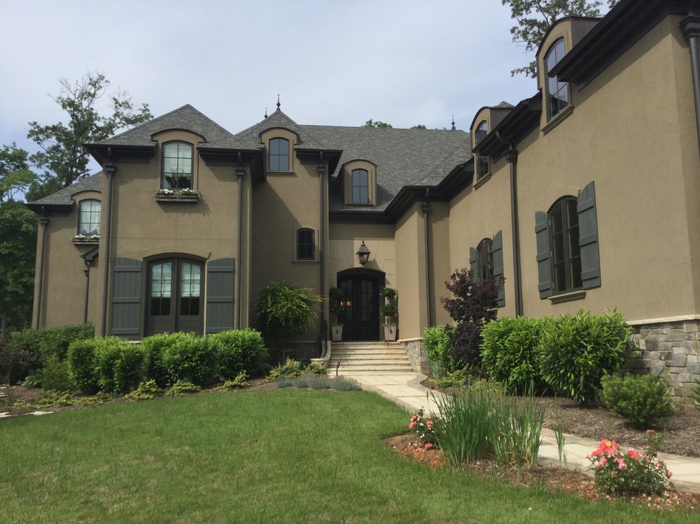 Example of a large classic beige two-story stucco house exterior design in Atlanta with a hip roof and a shingle roof