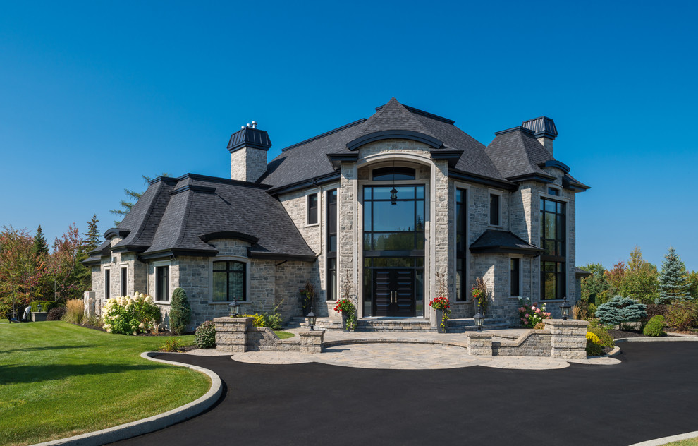 Идея дизайна: огромный, двухэтажный, серый частный загородный дом в классическом стиле с облицовкой из камня и крышей из гибкой черепицы