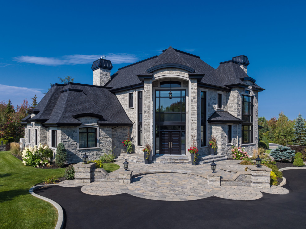 Aménagement d'une très grande façade de maison grise classique en pierre à un étage avec un toit en shingle.
