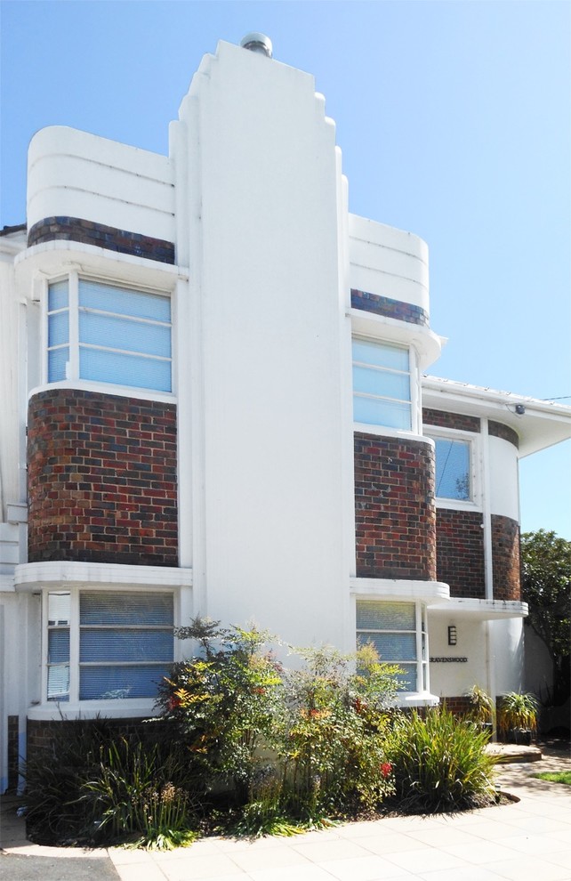 Mittelgroßes, Zweistöckiges Mid-Century Einfamilienhaus mit Backsteinfassade, weißer Fassadenfarbe, Walmdach und Ziegeldach in Melbourne