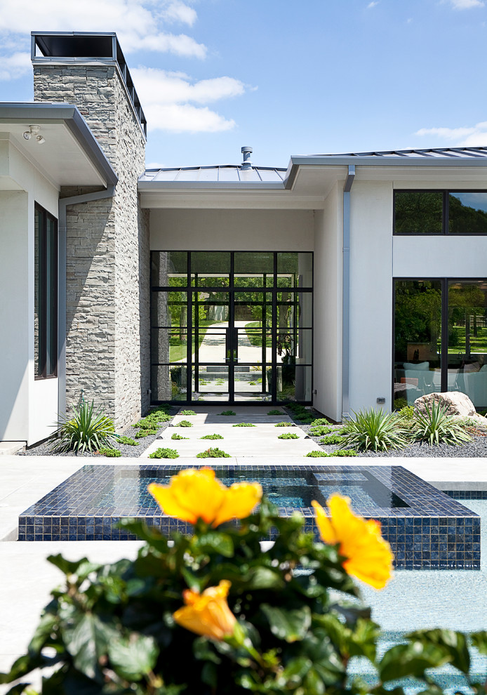 Diseño de fachada de casa blanca minimalista de tamaño medio de una planta con revestimiento de piedra, tejado a cuatro aguas y tejado de metal