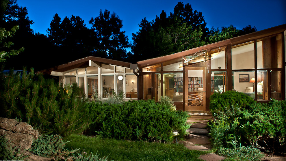 This is an example of a retro bungalow glass house exterior in Denver with a pitched roof.