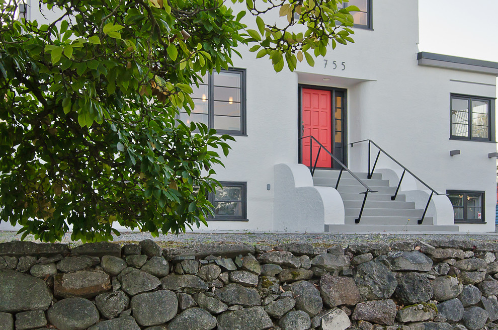 Cette image montre une grande façade de maison grise minimaliste en stuc à un étage avec un toit plat.