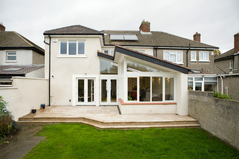 Aménagement d'une façade de maison blanche contemporaine en stuc de taille moyenne et à un étage avec un toit à quatre pans.