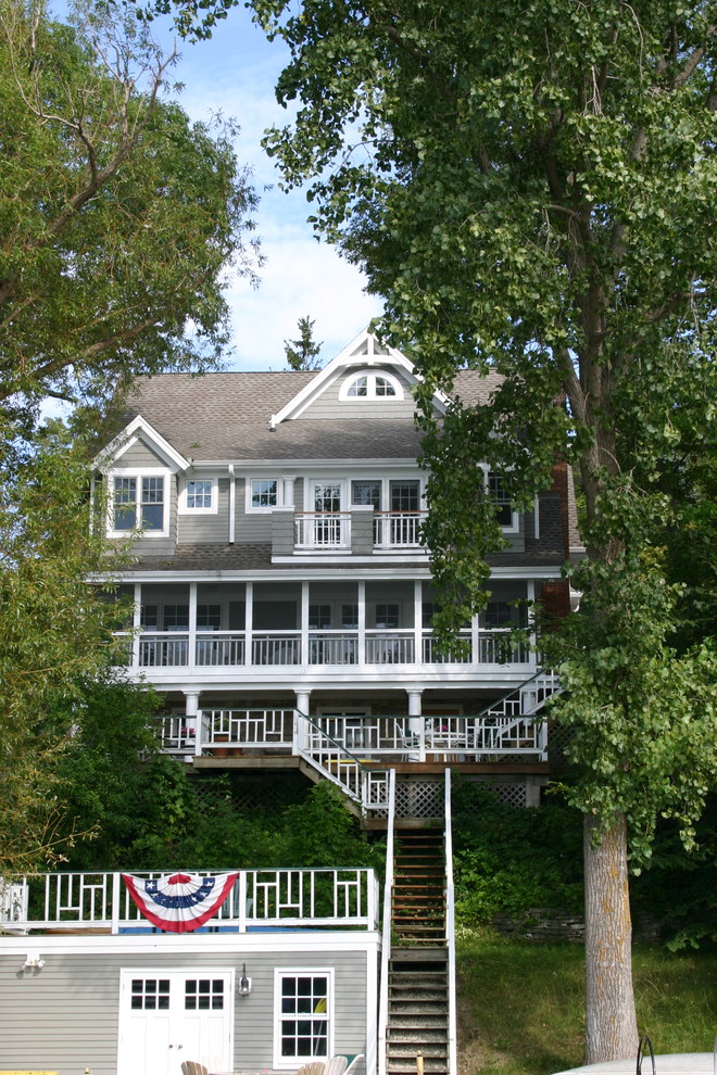 На фото: трехэтажный, серый, большой, деревянный дом в классическом стиле с двускатной крышей с