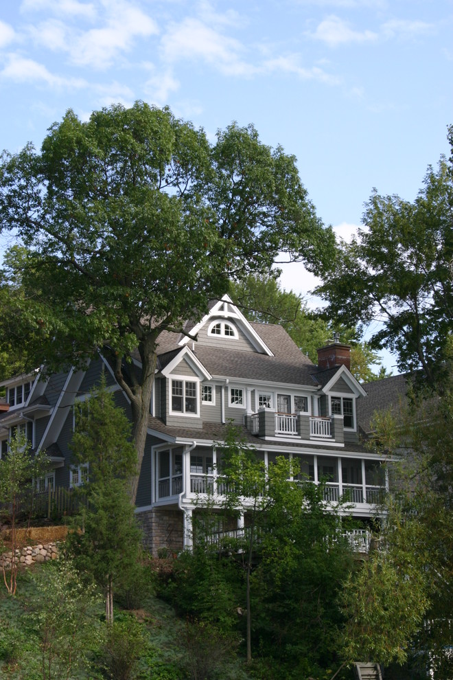 Foto della facciata di una casa grande grigia classica a tre piani con rivestimento in legno e tetto a capanna