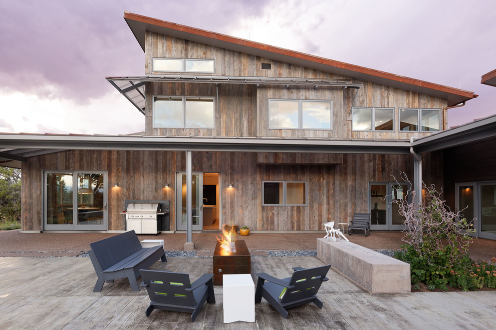 Réalisation d'une façade de maison marron minimaliste de taille moyenne et à un étage avec un revêtement mixte, un toit en appentis et un toit en métal.