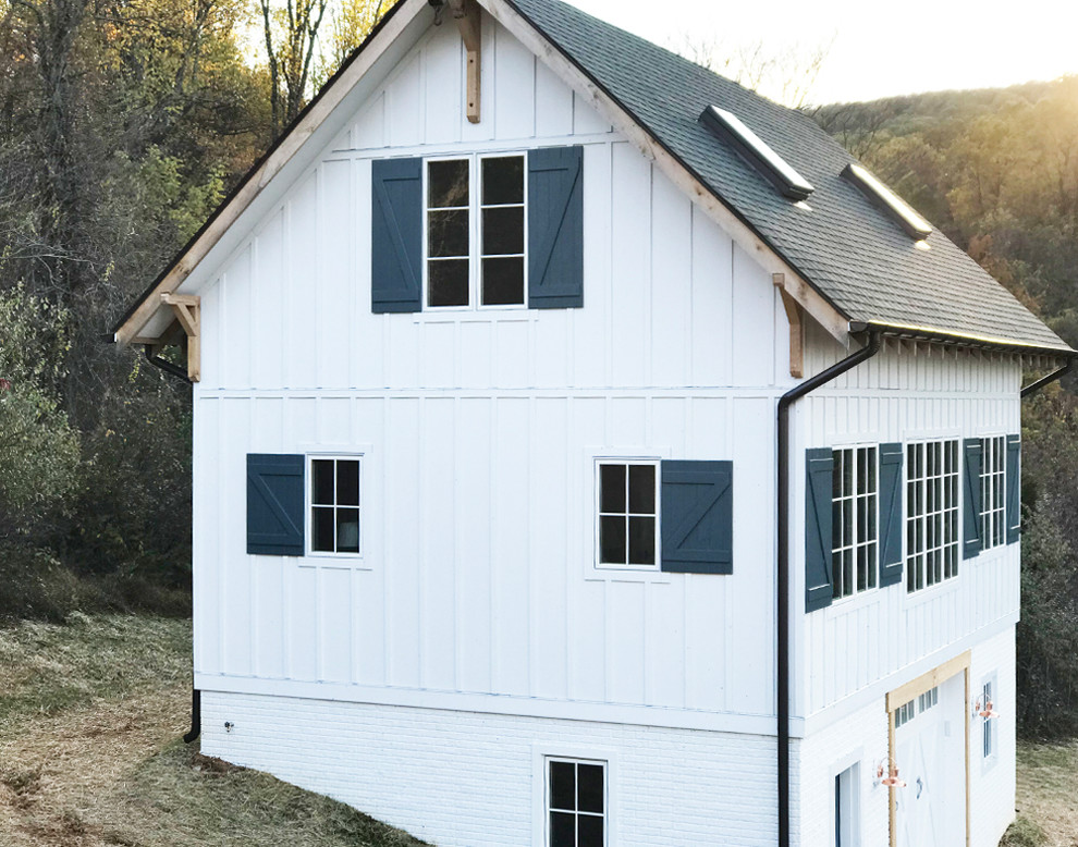 Foto på ett lantligt vitt hus, med tre eller fler plan, fiberplattor i betong och tak i shingel