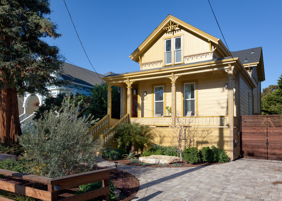 Idée de décoration pour une façade de maison jaune victorienne en bois de taille moyenne et à un étage avec un toit à deux pans et un toit en shingle.