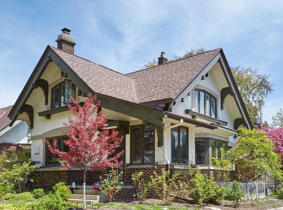 Réalisation d'une façade de maison beige craftsman en stuc de taille moyenne et à un étage avec un toit à deux pans et un toit en shingle.