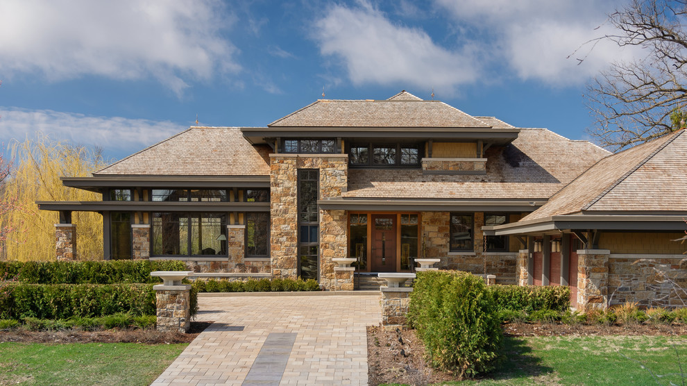 Immagine della facciata di una casa grande american style a due piani con rivestimento in pietra e tetto a padiglione