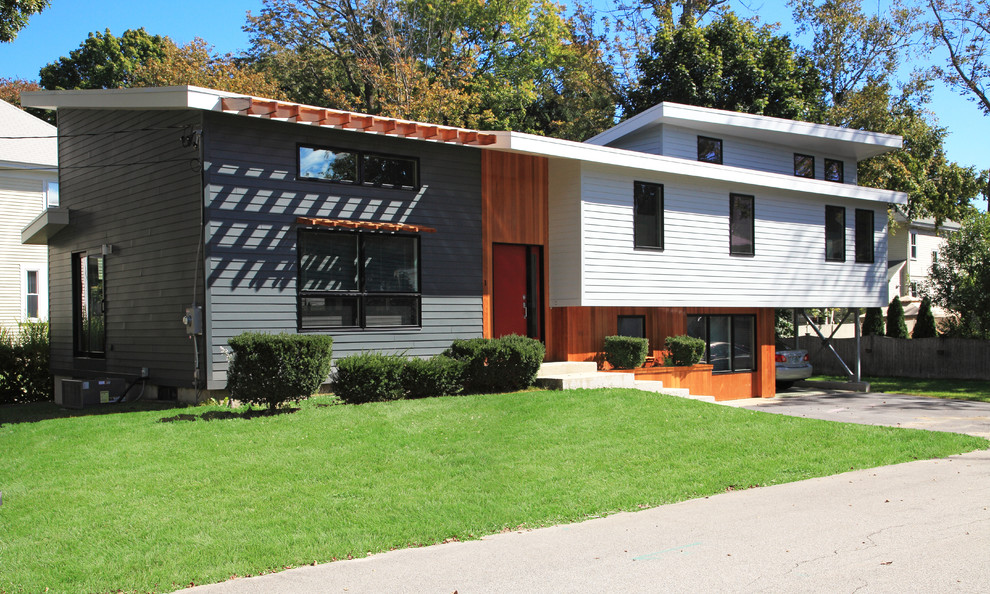 This is an example of a medium sized contemporary split-level house exterior in Boston with concrete fibreboard cladding.