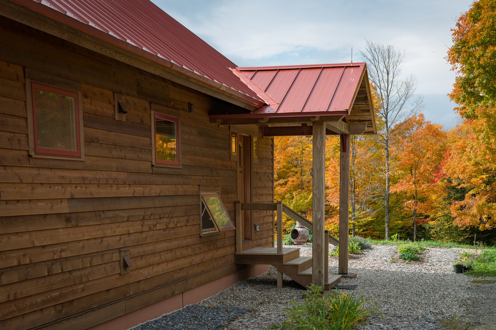 Esempio della facciata di una casa country a un piano di medie dimensioni con rivestimento in legno e tetto a capanna