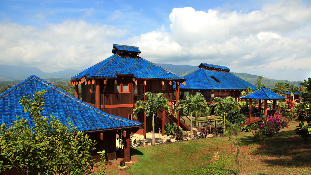 Cette photo montre une façade de maison exotique en bois à un étage avec un toit bleu.