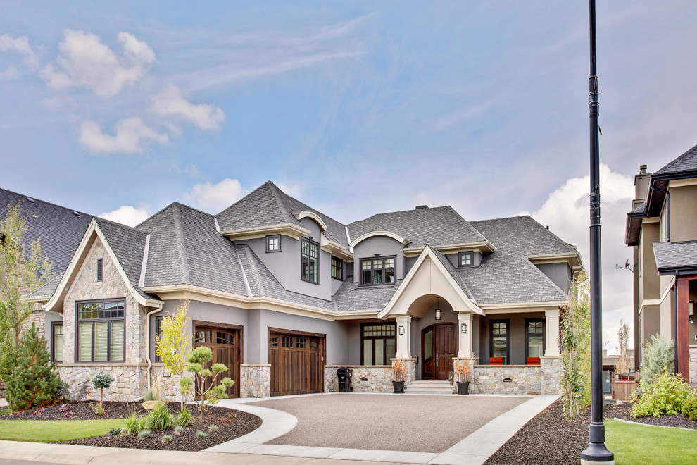 На фото: большой, серый, двухэтажный частный загородный дом в стиле кантри с комбинированной облицовкой, вальмовой крышей и крышей из гибкой черепицы с