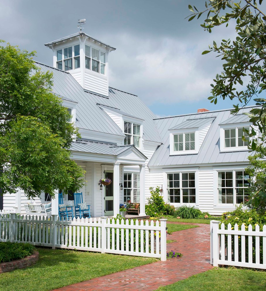 На фото: двухэтажный, белый частный загородный дом в стиле кантри с металлической крышей с