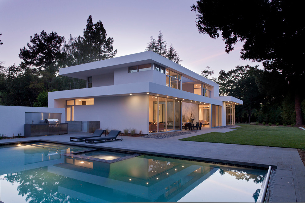 Идея дизайна: двухэтажный, белый, большой дом в стиле модернизм с плоской крышей и облицовкой из цементной штукатурки