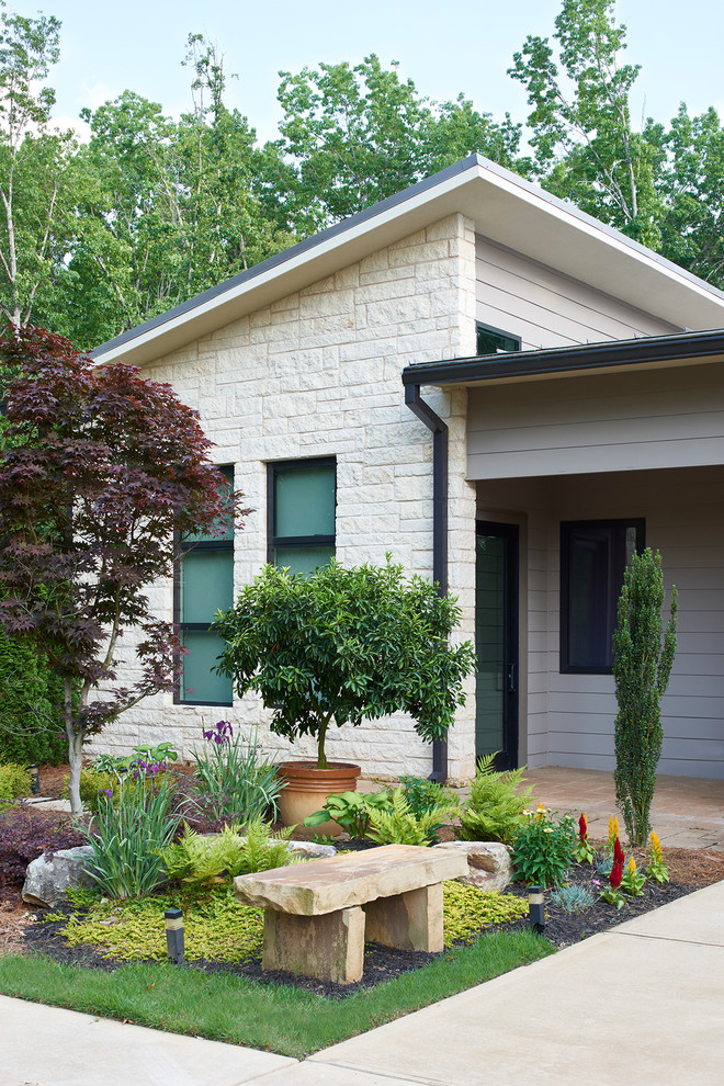 Cette photo montre une façade de maison beige moderne en pierre de taille moyenne et de plain-pied avec un toit plat et un toit en métal.