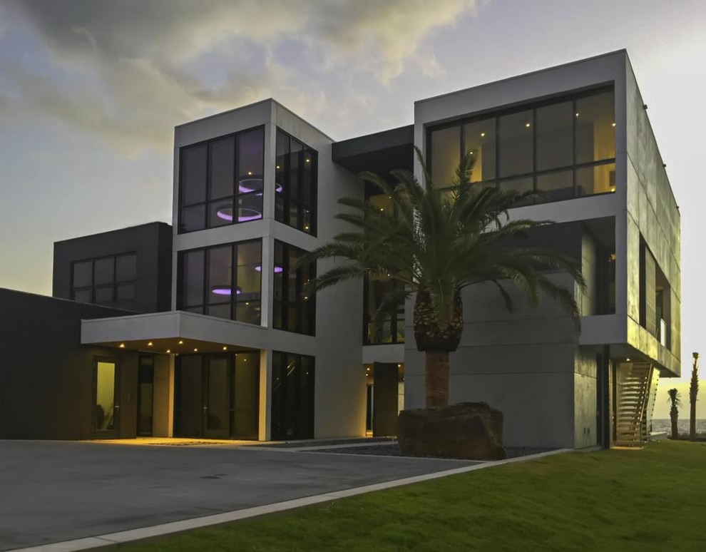 На фото: большой, трехэтажный, серый дом в стиле модернизм с облицовкой из бетона и плоской крышей с