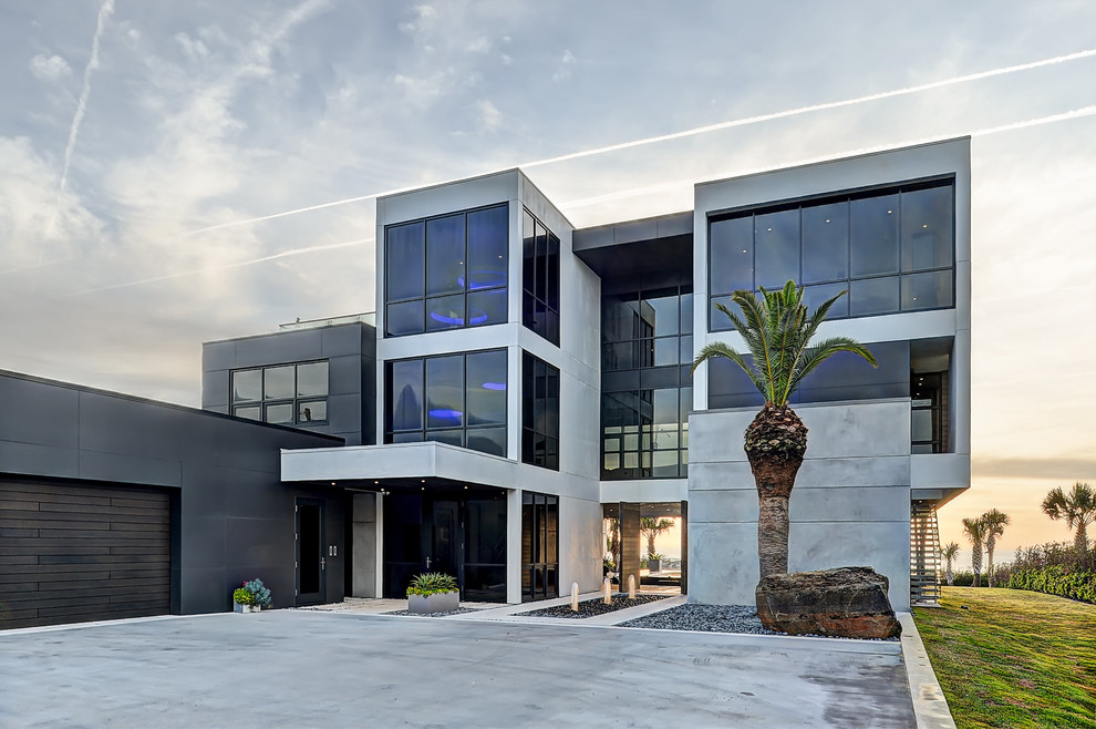 На фото: огромный, трехэтажный, серый частный загородный дом в современном стиле с облицовкой из бетона и плоской крышей с