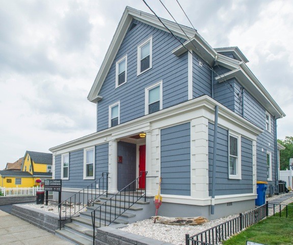 Cette image montre une façade de maison bleue design en bois à deux étages et plus avec un toit à quatre pans.