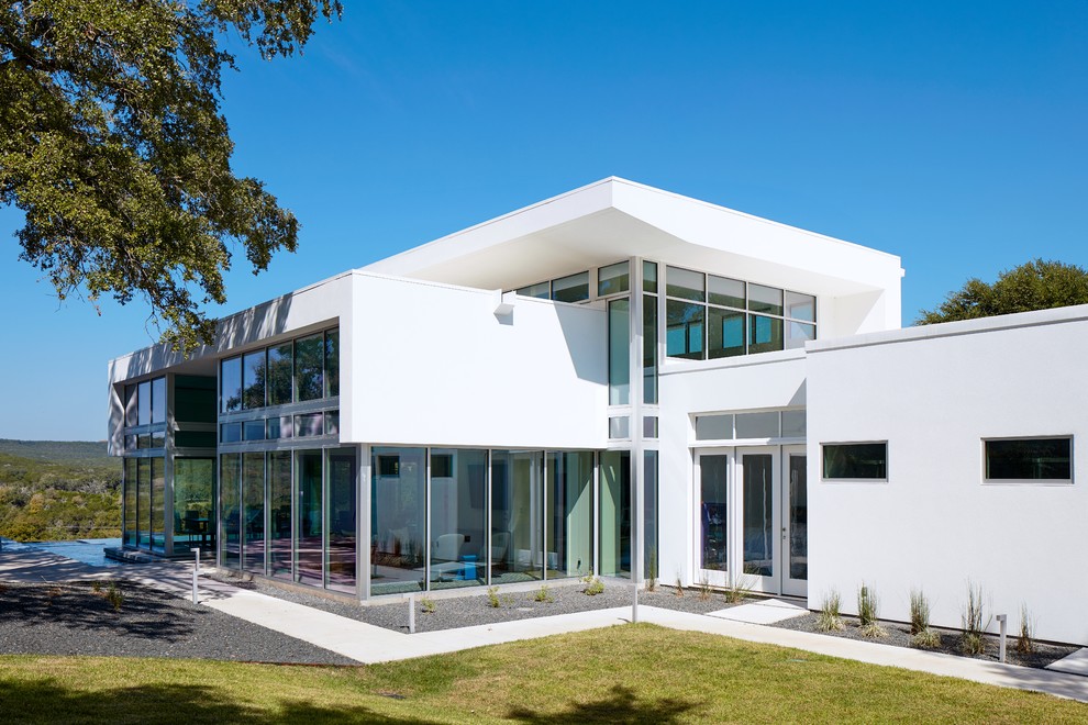Mittelgroßes, Zweistöckiges Modernes Haus mit Glasfassade, weißer Fassadenfarbe und Flachdach in Austin