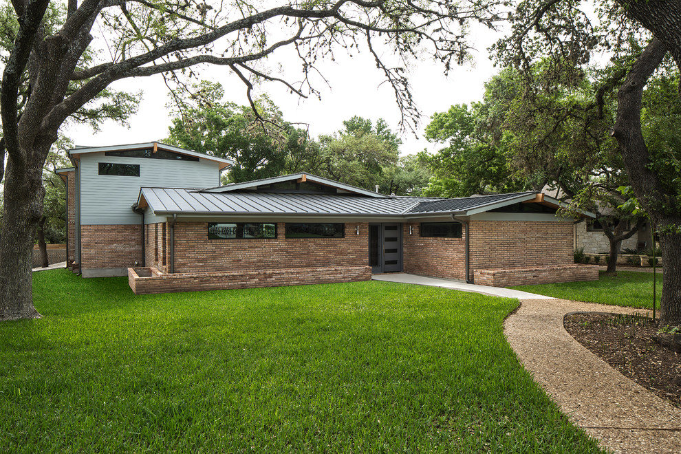 Large 1960s brown two-story brick exterior home idea in Austin with a hip roof