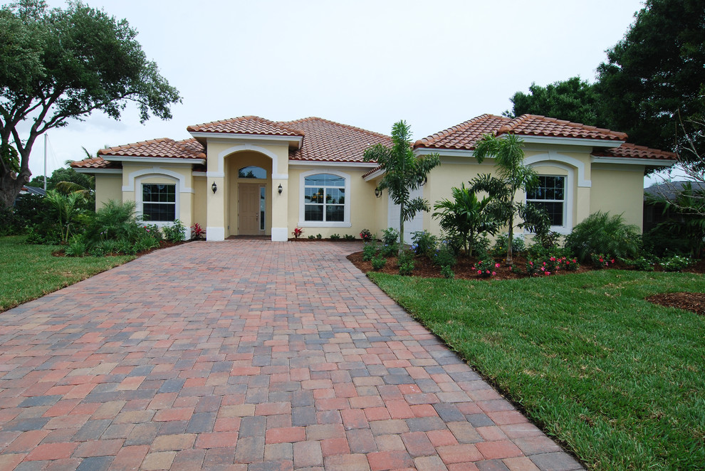 Photo of a beige classic bungalow render house exterior in Miami with a hip roof.