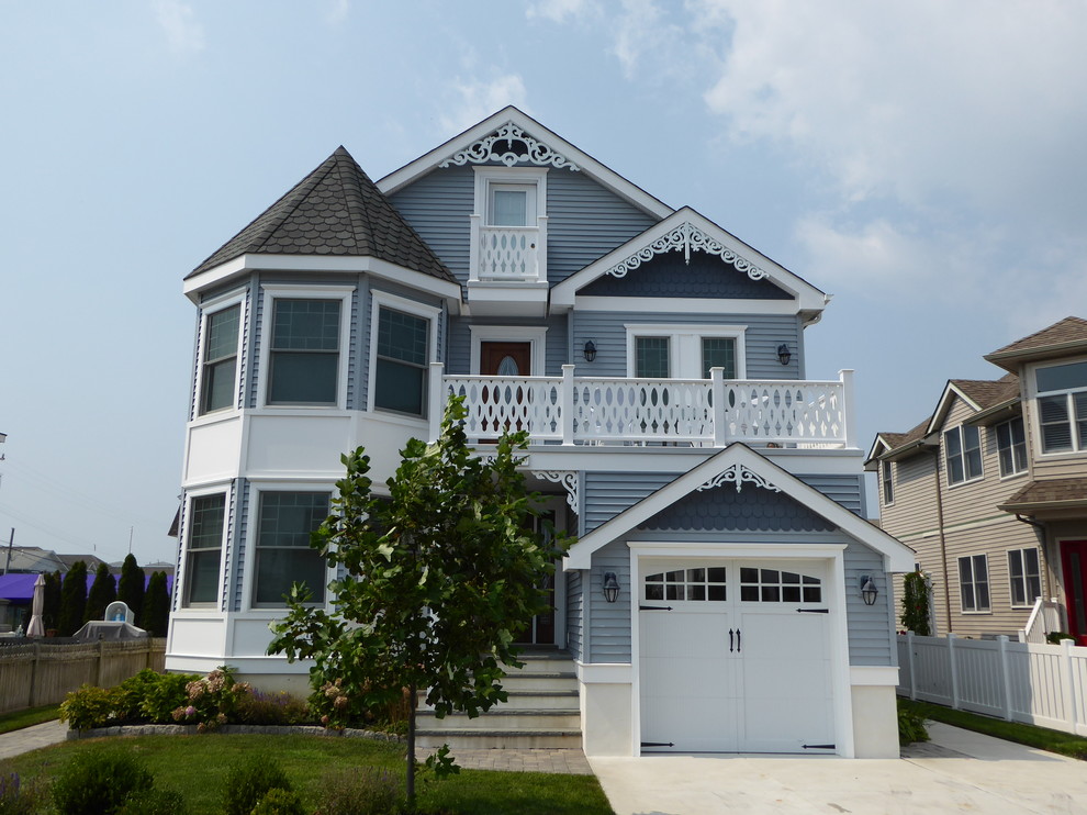 Foto de fachada de casa azul clásica grande de tres plantas con revestimiento de vinilo, tejado a dos aguas y tejado de teja de barro