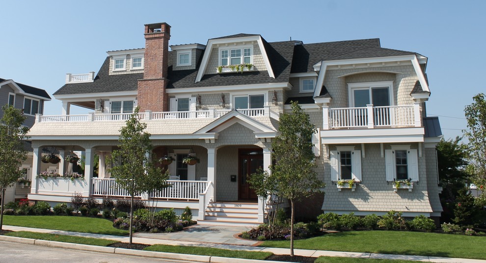 Example of an ornate beige three-story wood exterior home design in Philadelphia with a clipped gable roof
