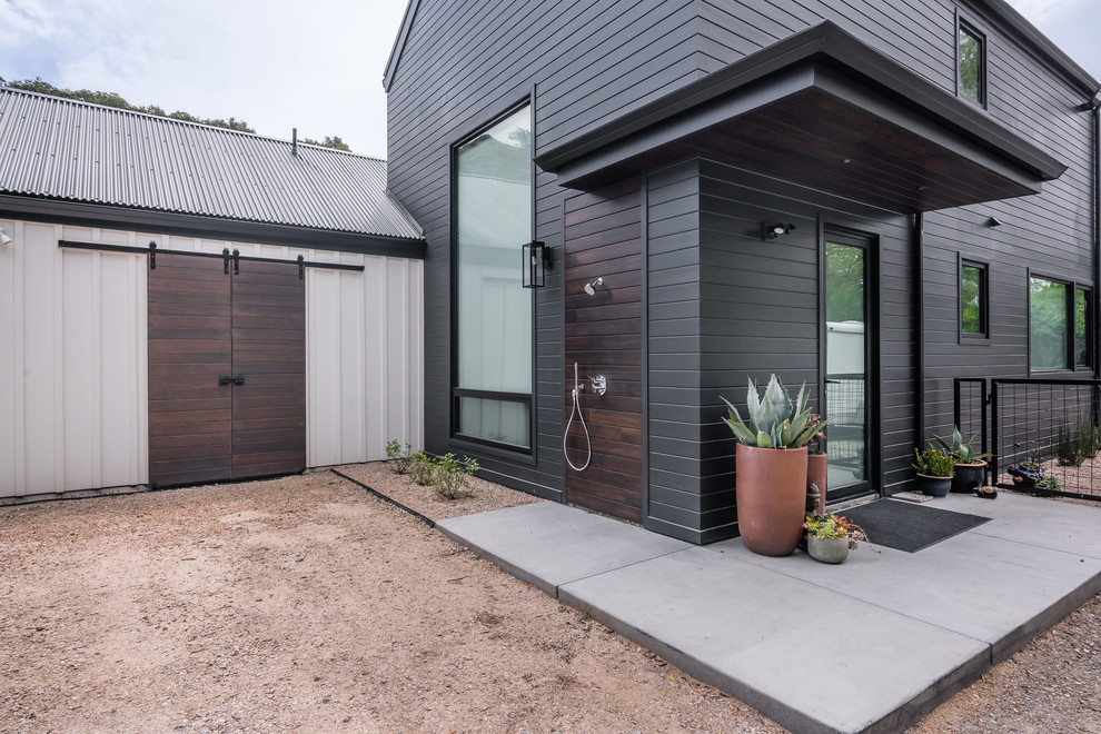 Idées déco pour une façade de maison noire campagne en bois de taille moyenne et à un étage avec un toit à deux pans et un toit en métal.