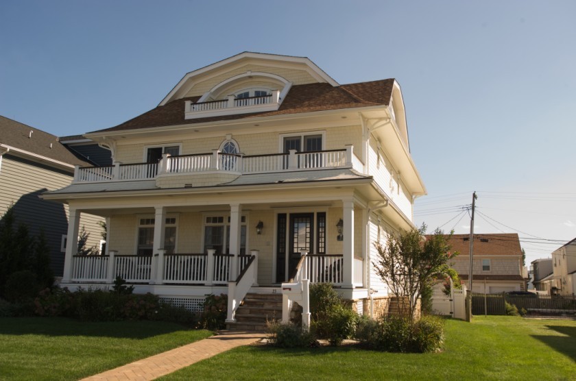 This is an example of a medium sized and yellow traditional two floor detached house in New York with wood cladding, a mansard roof and a shingle roof.