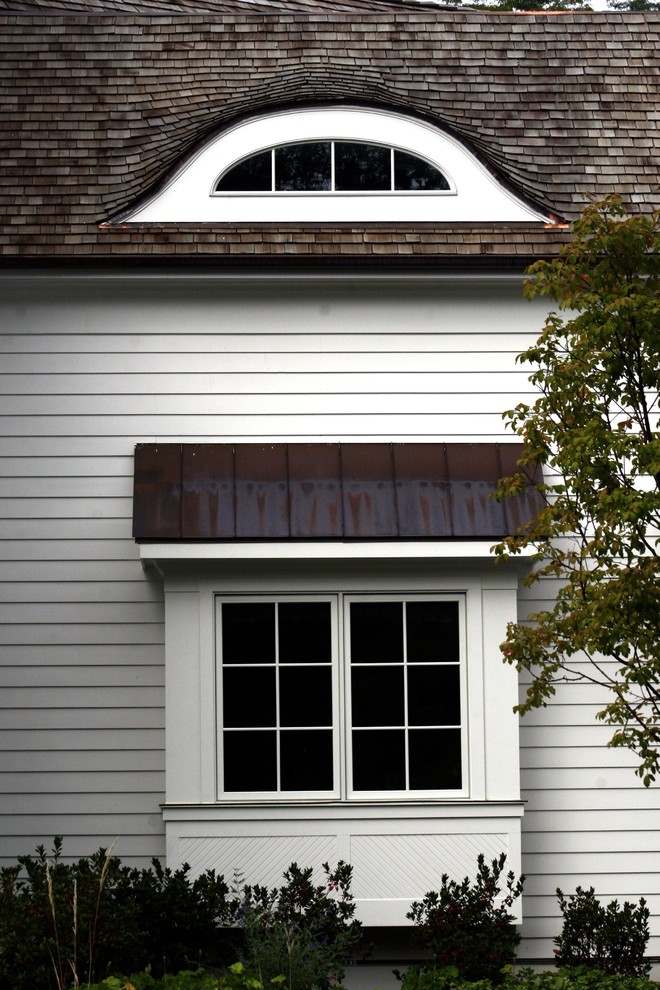 На фото: большой, двухэтажный, белый частный загородный дом в классическом стиле с облицовкой из винила, двускатной крышей и крышей из гибкой черепицы