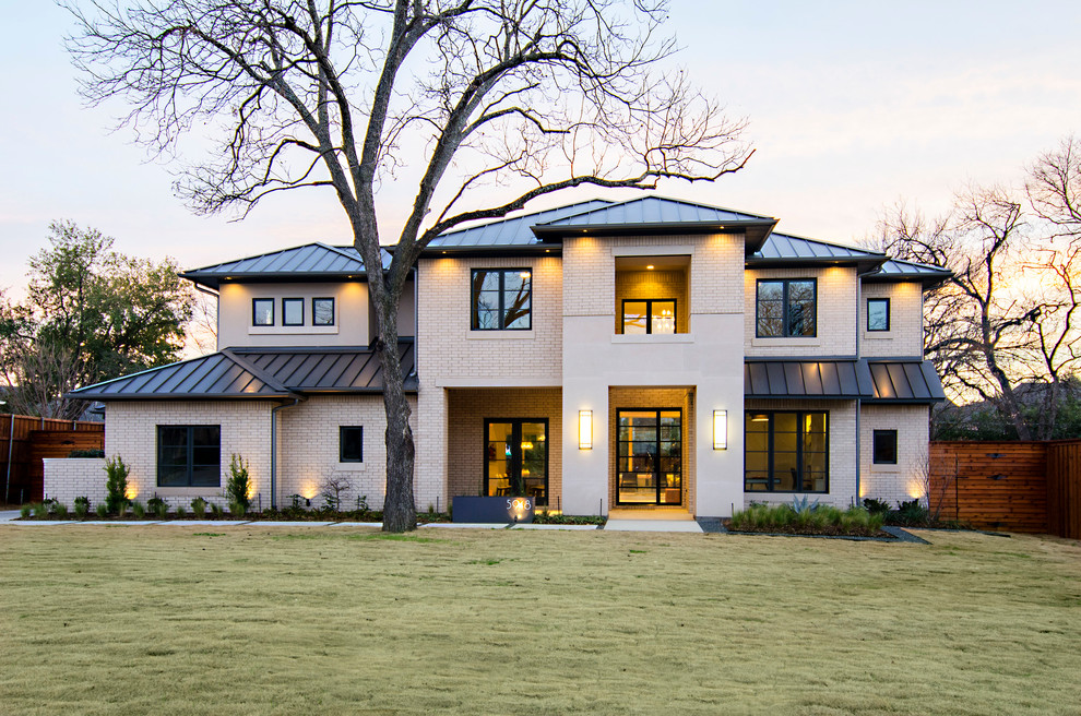 Inspiration for a transitional beige two-story brick exterior home remodel in Dallas with a hip roof and a metal roof