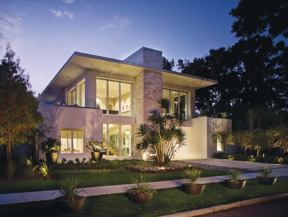 Réalisation d'une façade de maison blanche design en stuc de taille moyenne et à un étage.