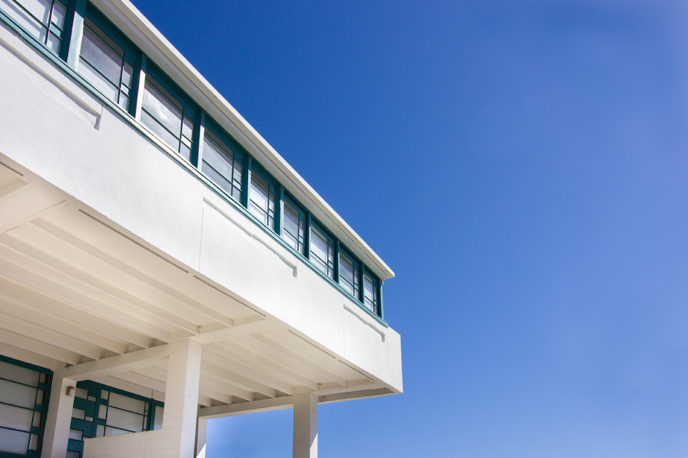 Cette image montre une grande façade de maison blanche minimaliste en béton à un étage avec un toit plat.