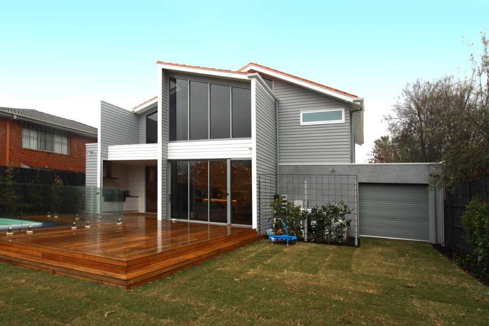 Cette photo montre une façade de maison grise tendance en bois de taille moyenne et à un étage avec un toit à deux pans et un toit en tuile.