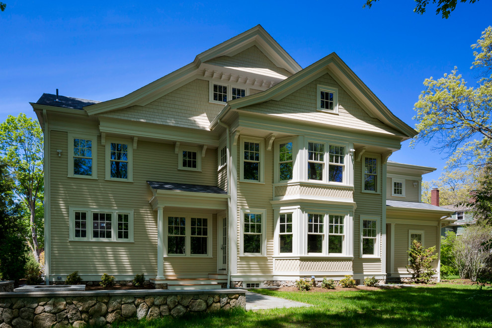 Diseño de fachada beige clásica grande de dos plantas con revestimiento de madera y tejado a dos aguas