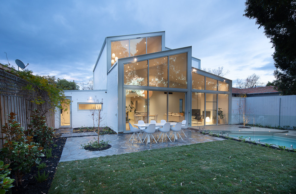 Inspiration pour une façade de maison grise en verre de taille moyenne et à un étage avec un toit à deux pans et un toit mixte.
