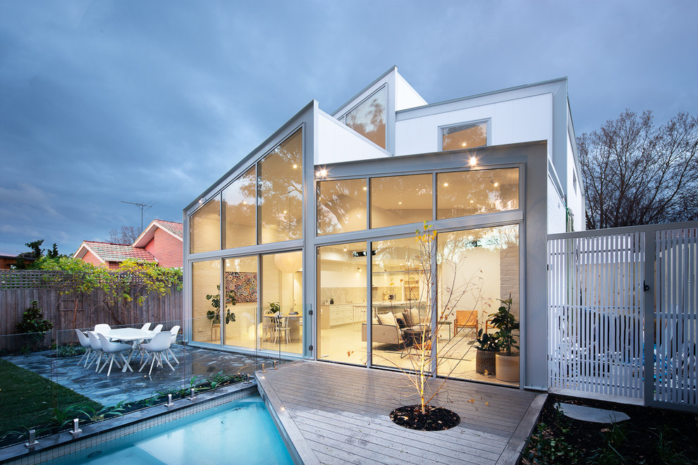 Aménagement d'une façade de maison grise en verre de taille moyenne et à un étage avec un toit à deux pans et un toit mixte.