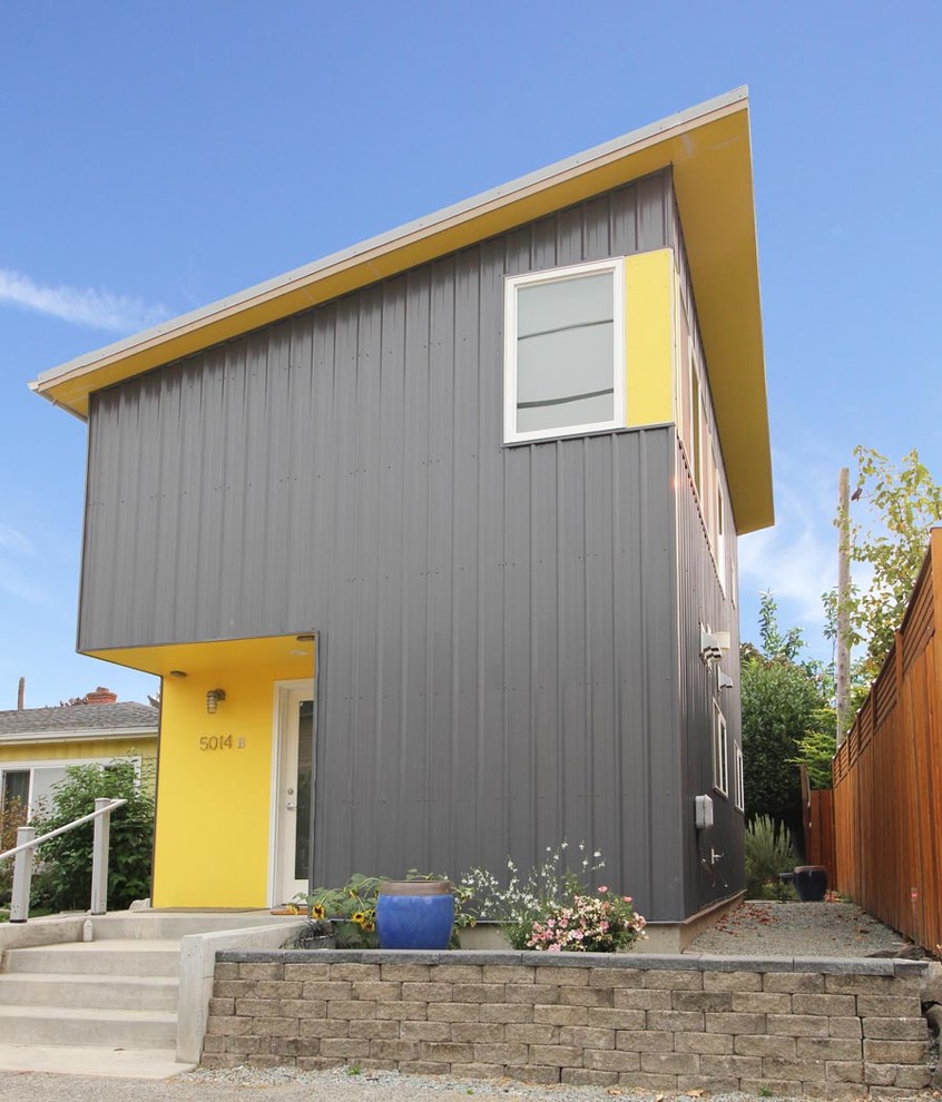 На фото: маленький, двухэтажный, серый частный загородный дом в современном стиле с облицовкой из металла, односкатной крышей и металлической крышей для на участке и в саду