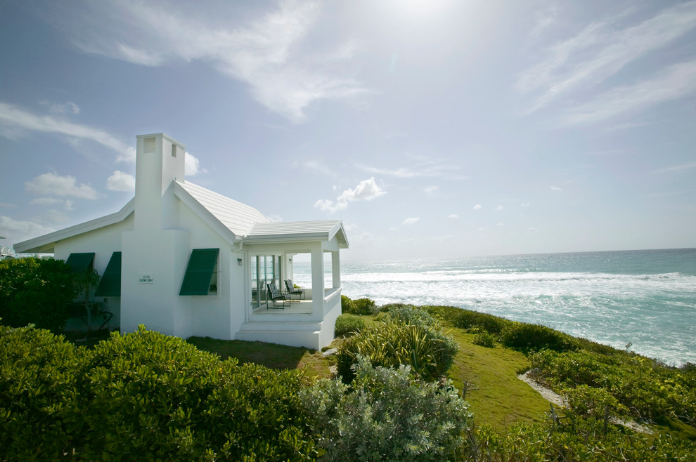 Cette photo montre une façade de maison blanche exotique de plain-pied.